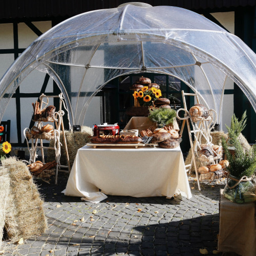Ein mit verschiedenen Broten gedeckter Tisch unter einem Regenschutz im Innenhof des Hofgut Mappen